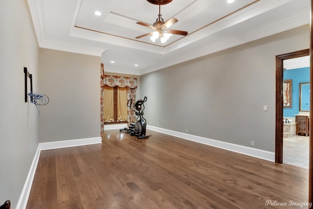 empty room featuring a tray ceiling, dark tile floors, ceiling fan, and crown molding