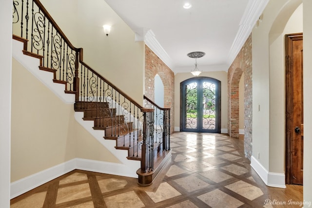 tiled foyer entrance with brick wall, french doors, and ornamental molding