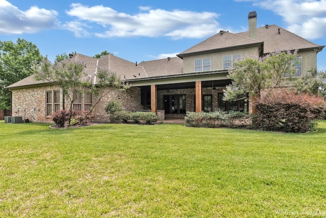 rear view of property featuring a lawn and central AC unit