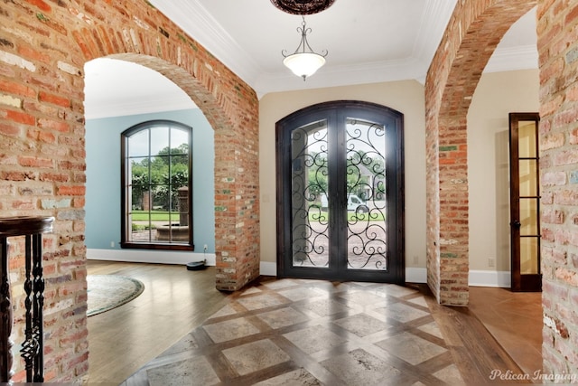 tiled entryway featuring french doors, brick wall, and ornamental molding