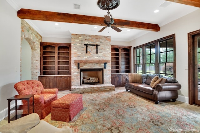 tiled living room with built in features, beamed ceiling, ceiling fan, and a brick fireplace