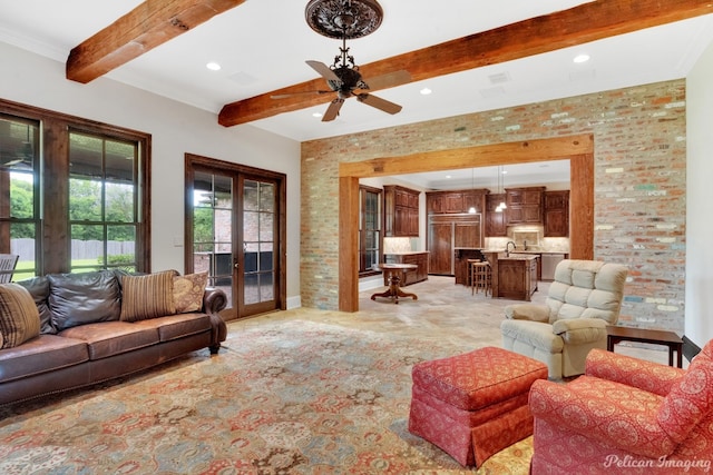 living room with beamed ceiling, crown molding, light tile floors, ceiling fan, and sink