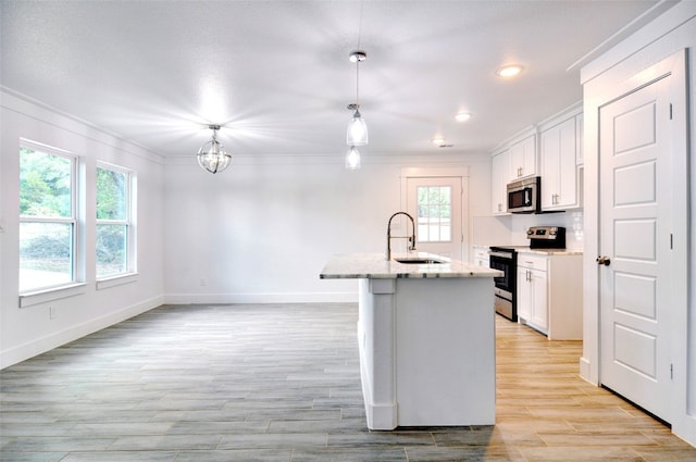 kitchen featuring white cabinets, appliances with stainless steel finishes, hanging light fixtures, and sink