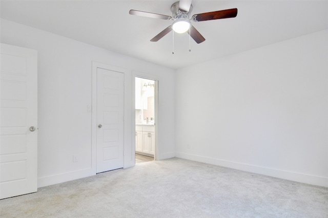 unfurnished bedroom featuring ceiling fan, light colored carpet, and ensuite bathroom