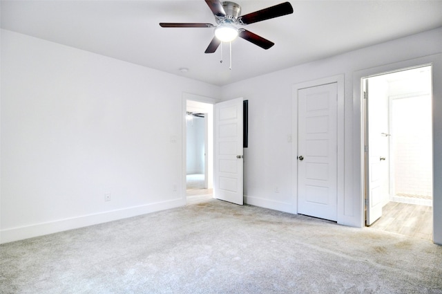 unfurnished bedroom featuring light carpet, connected bathroom, and ceiling fan