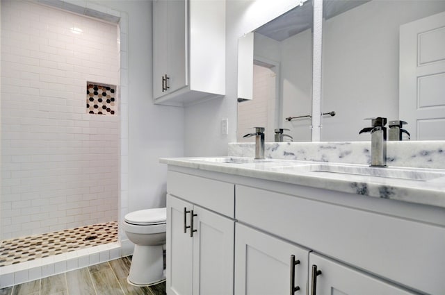 bathroom featuring tiled shower, toilet, hardwood / wood-style flooring, and oversized vanity