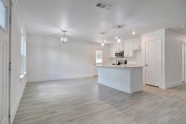 kitchen with appliances with stainless steel finishes, pendant lighting, light wood-type flooring, and white cabinets