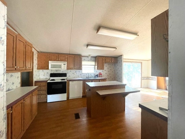 kitchen with white appliances, sink, hardwood / wood-style flooring, and a wealth of natural light