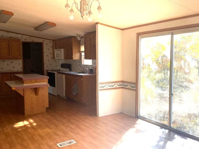 kitchen with stove, a notable chandelier, light hardwood / wood-style flooring, backsplash, and sink