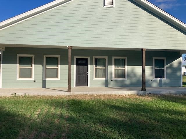 rear view of property with a porch and a lawn