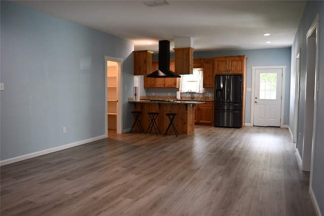 kitchen with wall chimney range hood, sink, dark hardwood / wood-style floors, and black refrigerator