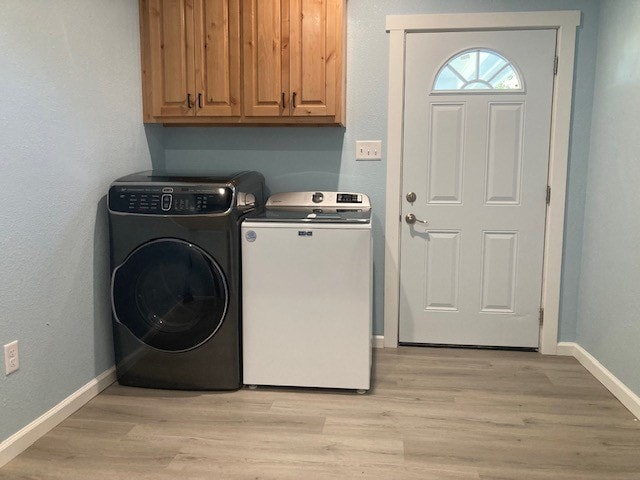 laundry room featuring cabinets, light hardwood / wood-style flooring, and washing machine and clothes dryer