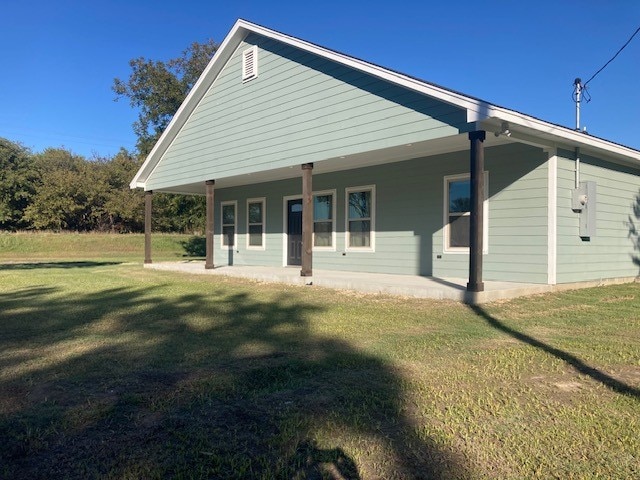 back of property featuring covered porch and a yard