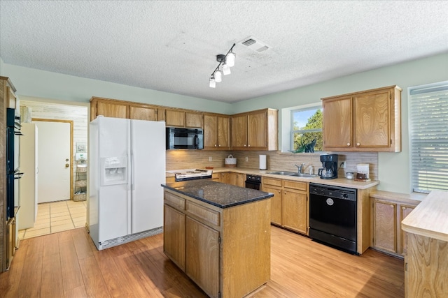 kitchen with tasteful backsplash, a kitchen island, light hardwood / wood-style flooring, black appliances, and a textured ceiling