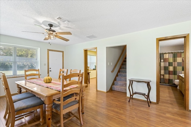 dining room with ceiling fan, light hardwood / wood-style flooring, and a textured ceiling