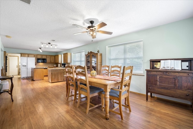 dining area featuring light hardwood / wood-style floors, a textured ceiling, ceiling fan, and track lighting