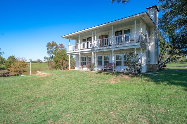 rear view of property featuring a lawn and a balcony