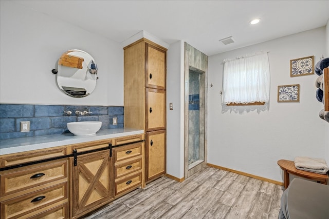 bathroom with vanity, tasteful backsplash, hardwood / wood-style flooring, and walk in shower