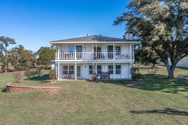 back of house with a lawn and a balcony