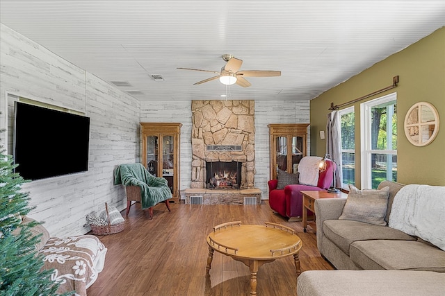 living room with ceiling fan, wood walls, a fireplace, and hardwood / wood-style flooring