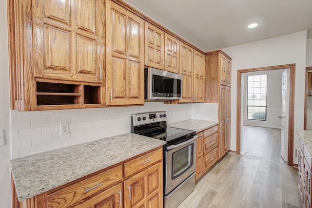 kitchen featuring decorative backsplash, light hardwood / wood-style flooring, stainless steel appliances, and light stone counters