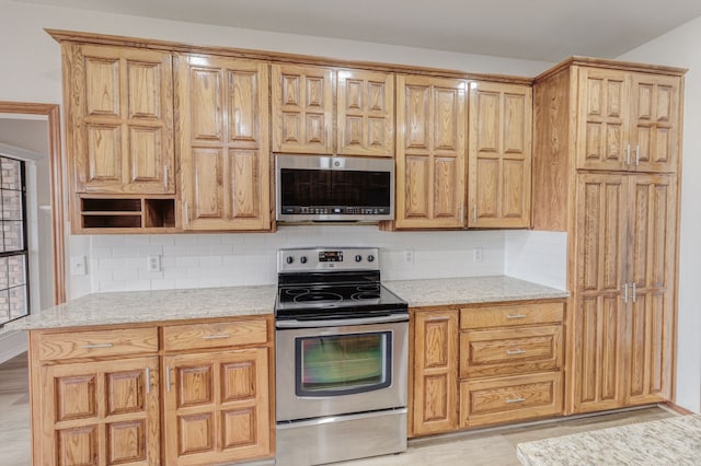 kitchen with decorative backsplash, appliances with stainless steel finishes, and light stone counters