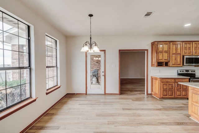 kitchen with plenty of natural light, light hardwood / wood-style flooring, stainless steel appliances, and a notable chandelier