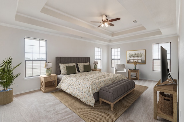 carpeted bedroom featuring multiple windows, ceiling fan, and a raised ceiling