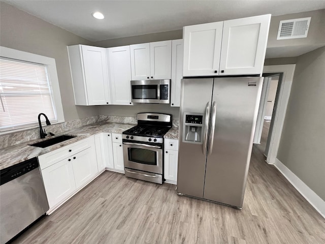 kitchen with stainless steel appliances, white cabinetry, and sink