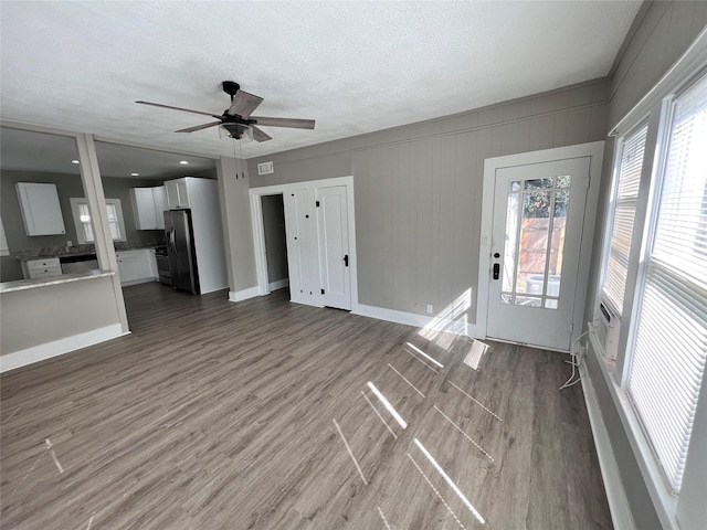 unfurnished living room with hardwood / wood-style floors, a textured ceiling, and ceiling fan