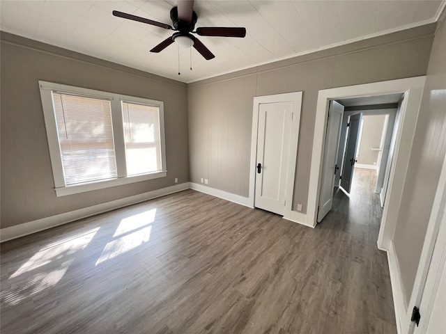 unfurnished bedroom featuring ornamental molding, dark wood-type flooring, and ceiling fan