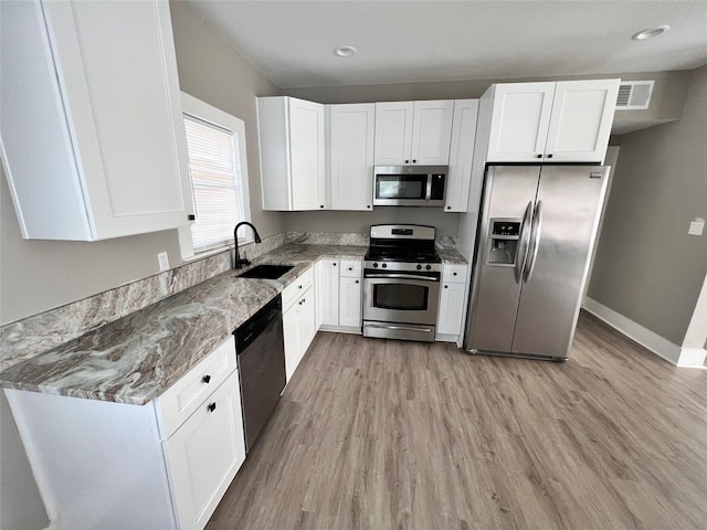 kitchen featuring light stone counters, white cabinets, light hardwood / wood-style floors, and appliances with stainless steel finishes