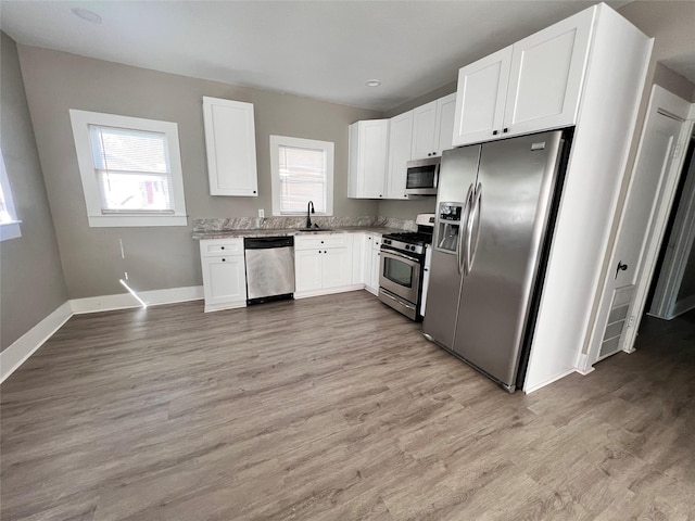 kitchen with white cabinetry, a healthy amount of sunlight, appliances with stainless steel finishes, and sink