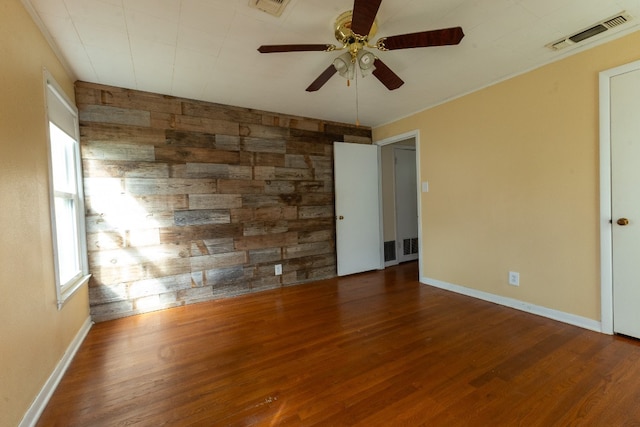 unfurnished room featuring wood walls, ceiling fan, and dark wood-type flooring