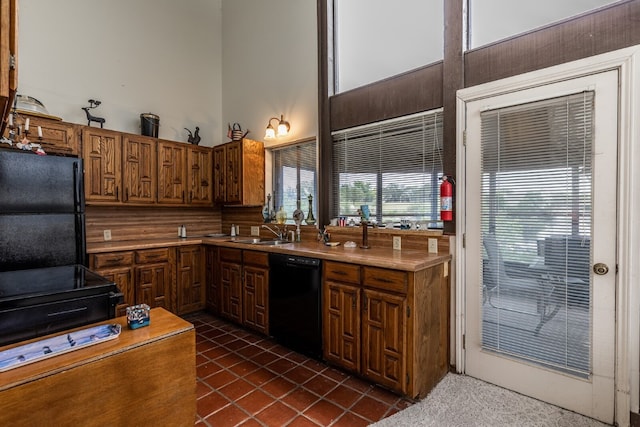 kitchen featuring sink, black appliances, dark tile flooring, and a high ceiling