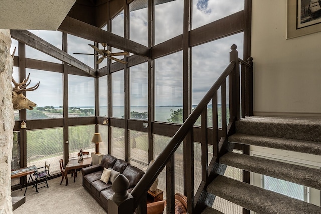 stairs featuring a high ceiling, ceiling fan, and a water view