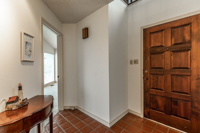 entryway featuring dark tile floors and a textured ceiling