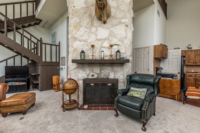 carpeted living room with a high ceiling and a stone fireplace