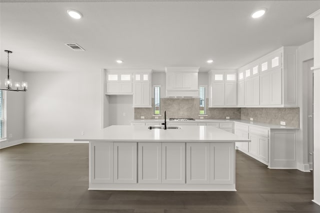 kitchen with pendant lighting, white cabinetry, an island with sink, sink, and a chandelier