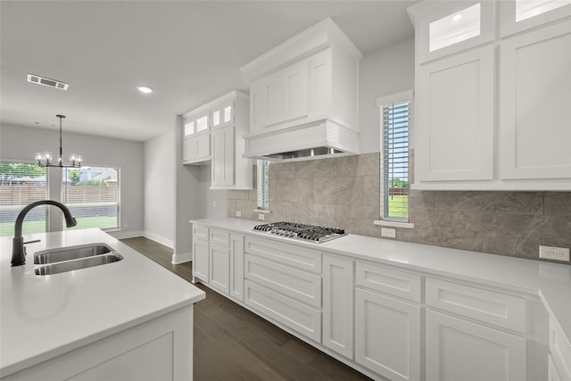 kitchen featuring white cabinets, sink, hanging light fixtures, stainless steel gas cooktop, and a notable chandelier