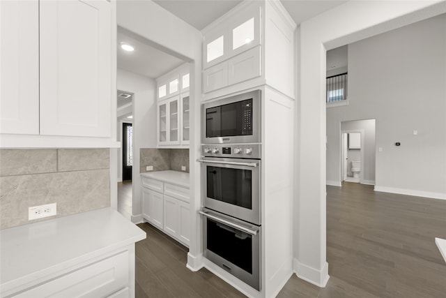 kitchen with decorative backsplash, dark wood-type flooring, white cabinets, and built in microwave