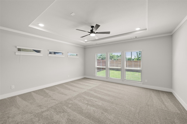 unfurnished room featuring a raised ceiling, ceiling fan, crown molding, and carpet floors