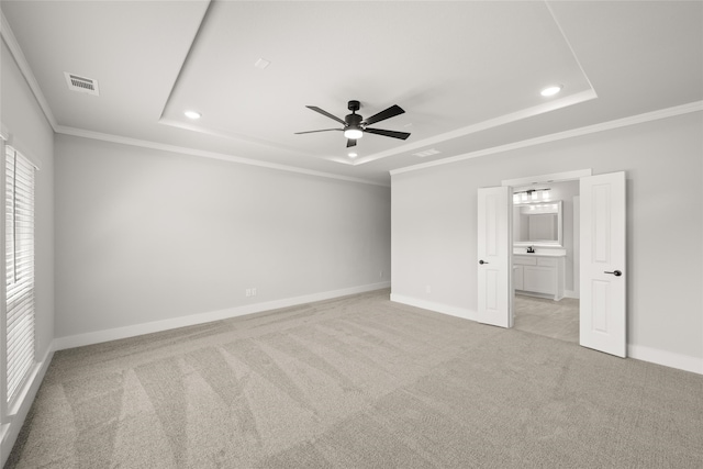 unfurnished bedroom with a raised ceiling, ceiling fan, light carpet, and ornamental molding