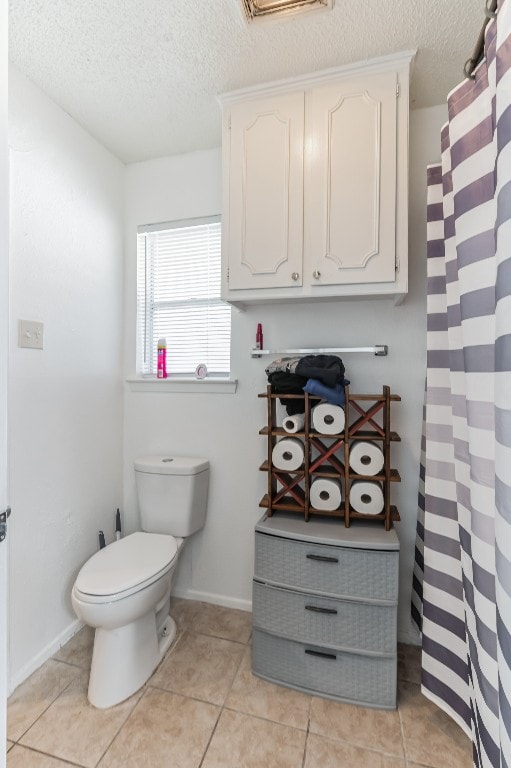 bathroom featuring tile flooring, toilet, and a textured ceiling