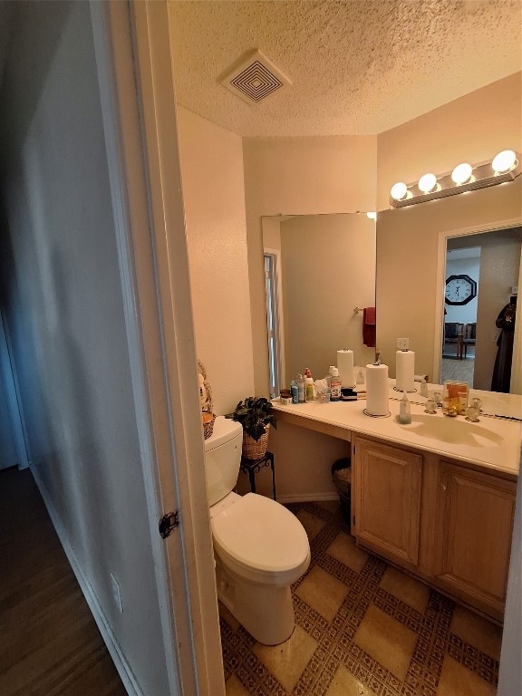 bathroom with toilet, a textured ceiling, and vanity