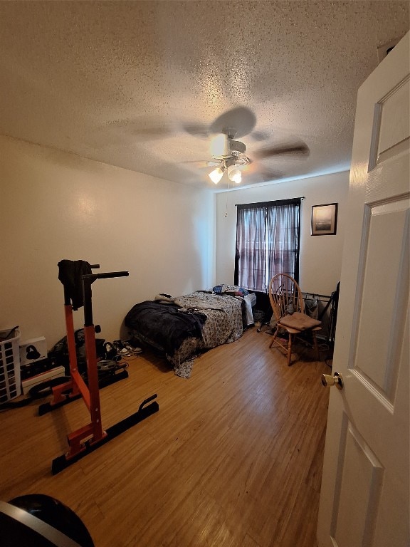 bedroom with ceiling fan, a textured ceiling, and wood-type flooring