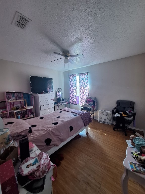 bedroom with ceiling fan, a textured ceiling, and hardwood / wood-style flooring