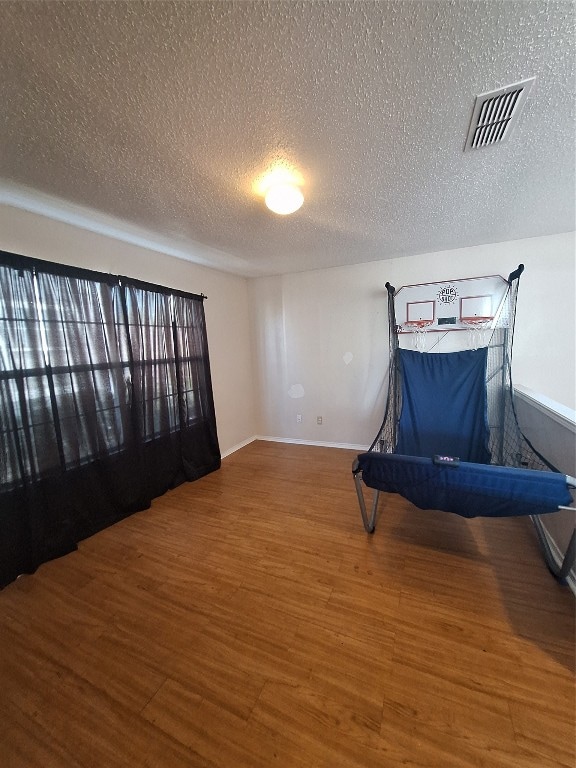 unfurnished bedroom with a textured ceiling and dark hardwood / wood-style flooring