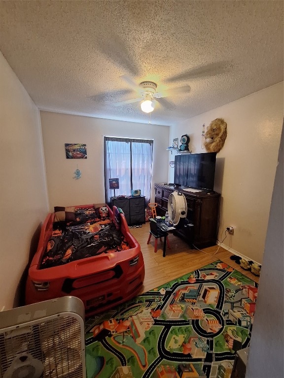 bedroom with a textured ceiling, ceiling fan, and hardwood / wood-style flooring