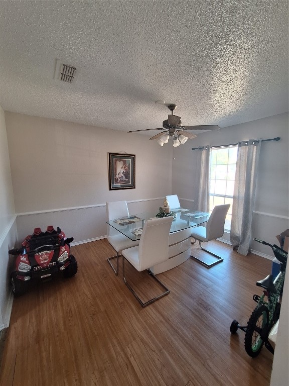 living room featuring ceiling fan, a textured ceiling, and wood-type flooring